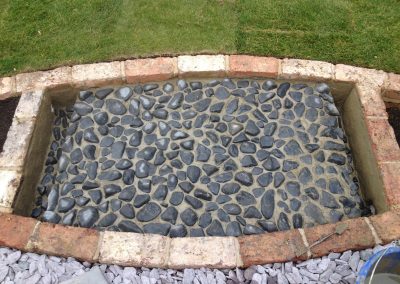 Black pebble and Victorian brick pond. Family garden Brighton